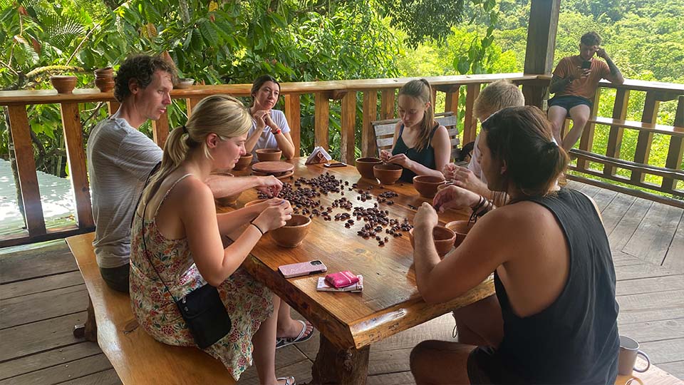 a group of people around a table handling cocal beans