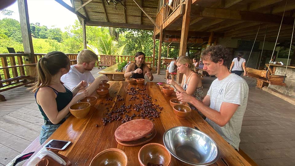a group of people around a table handling cocal beans